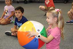 Kindergarten student holding ball in classroom